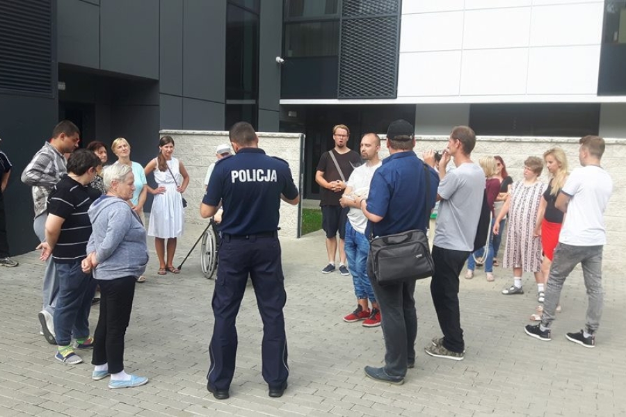 Uczestnicy stojący w kręgu, słuchający przemówienia funkcjonariusza policji
