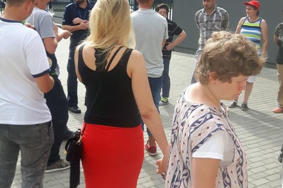 Uczestnicy słuchający przemówienia funkcjonariusza policji przed komisariatem