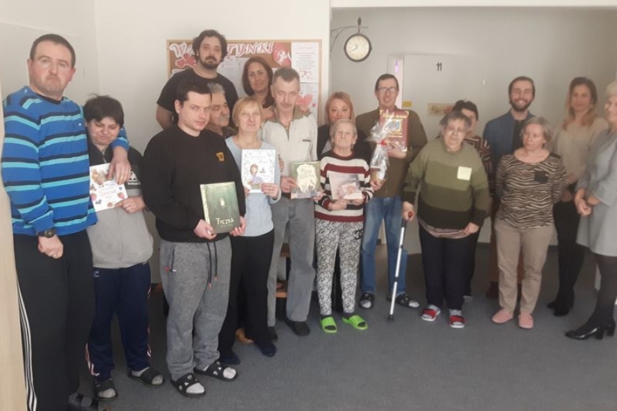 Grupa uczestników pozujących do zdjęcie z książkami. 