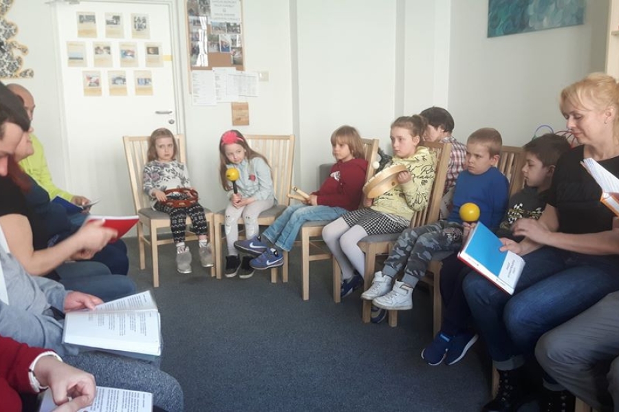 Uczestnicy siedzący w kręgu czytając dzieciom