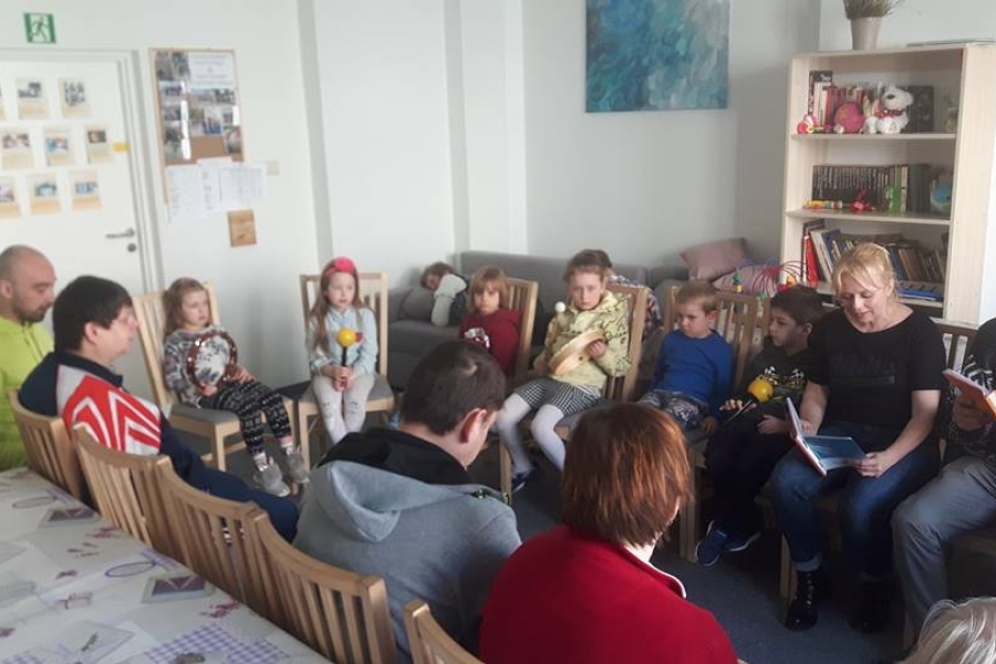 Uczestnicy siedzący w kręgu czytając dzieciom