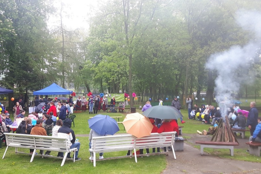 Goście siedzący na ławce podczas wydarzenia na tle ogniska