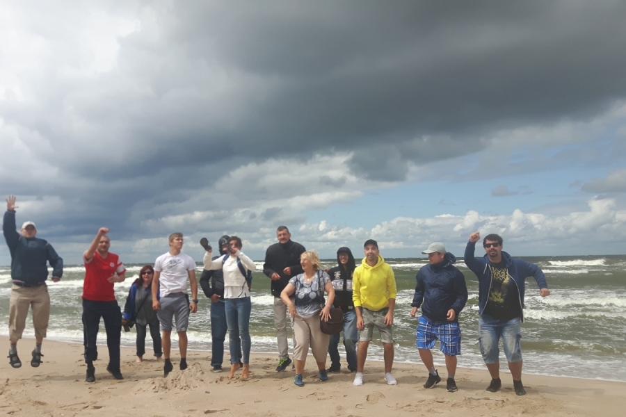 Grupa podskakujących uczestników na tle morza.