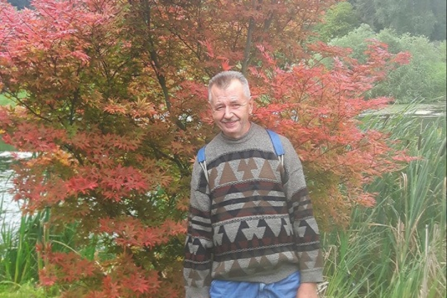 Uczestnik stojący pod krzewem koloru czerwonego na tle stawu.