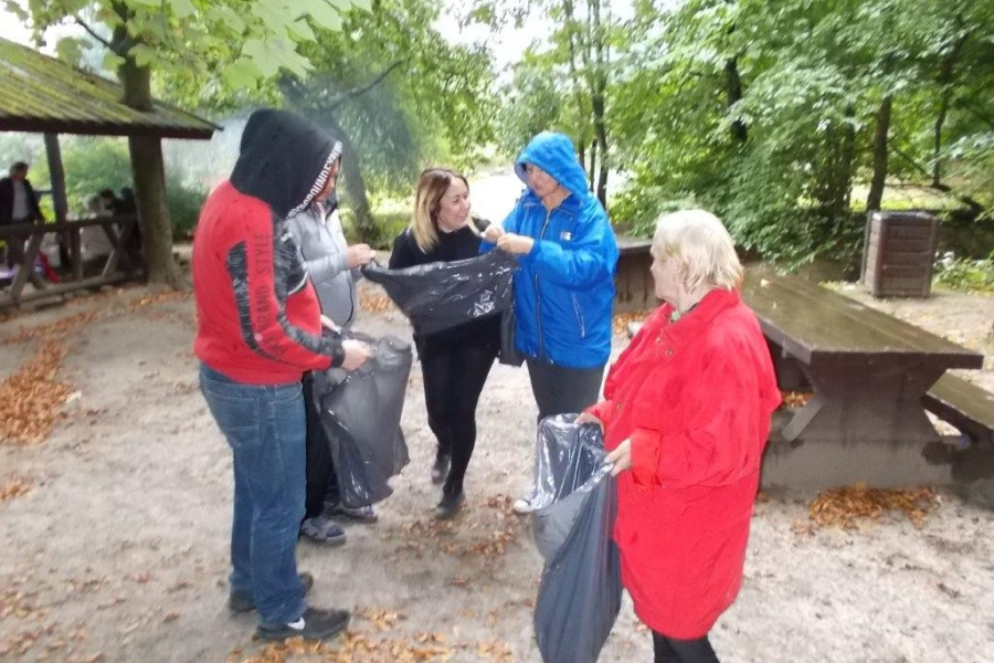 Uczestnicy wraz z terapeutką przygotowujący się do zbierania śmieci w lesie