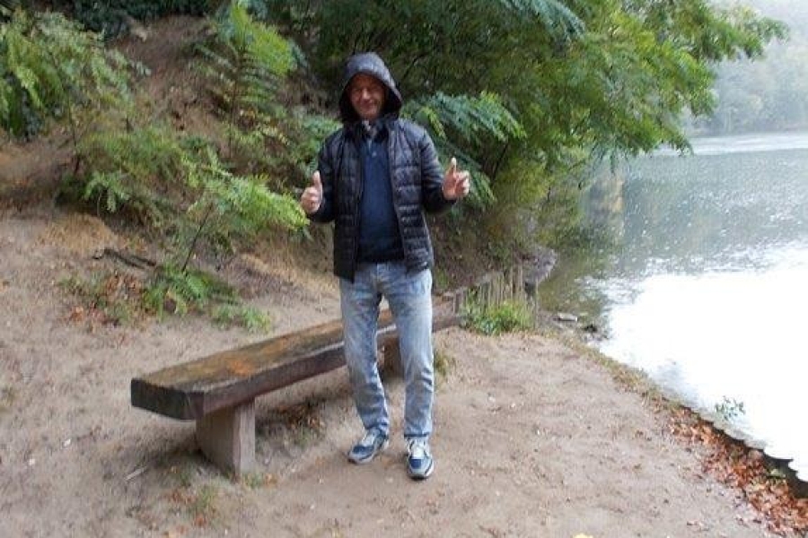 Uczestnik z kciukami w górze przy ławce na tle jeziora