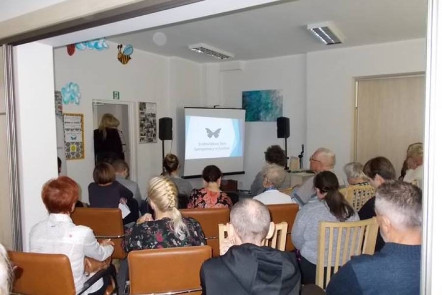 Grupa uczestników wraz z gośćmi siedzący przy stolikach