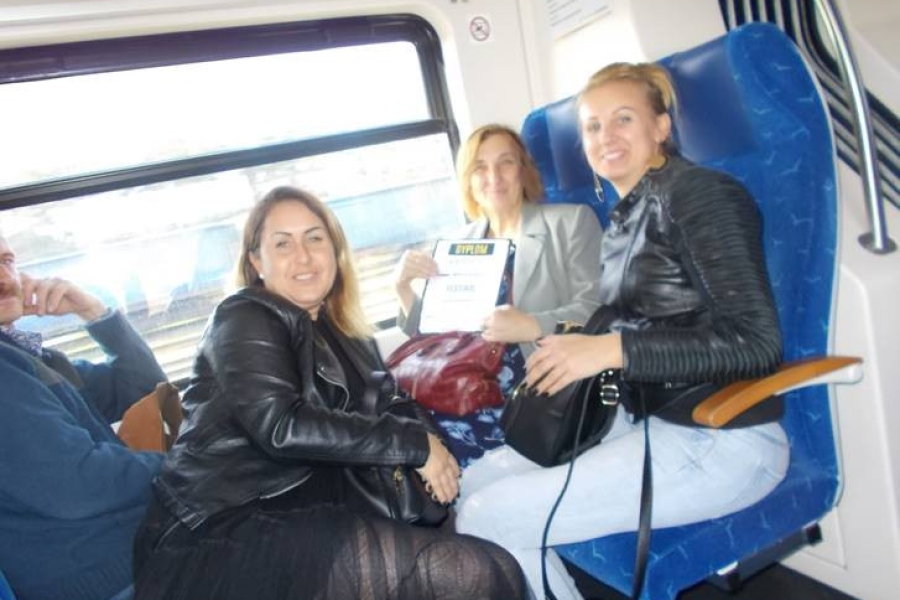 Uczestniczka chwaląca się dyplomem w obecności terapeutek w pociągu