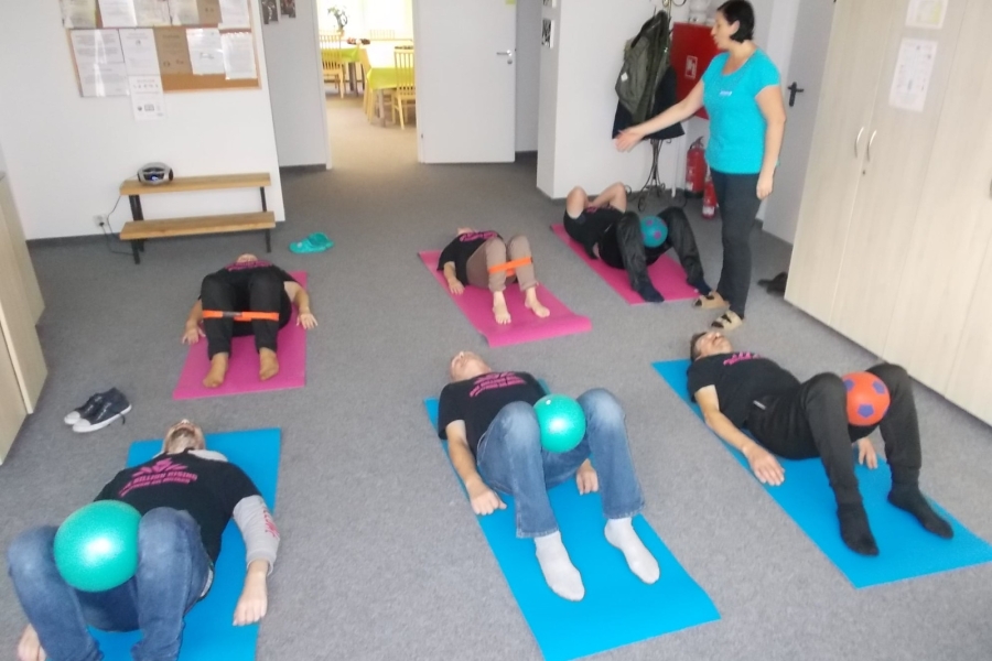 Uczestnicy leżący na karimatach podczas ćwiczeń z piłkami