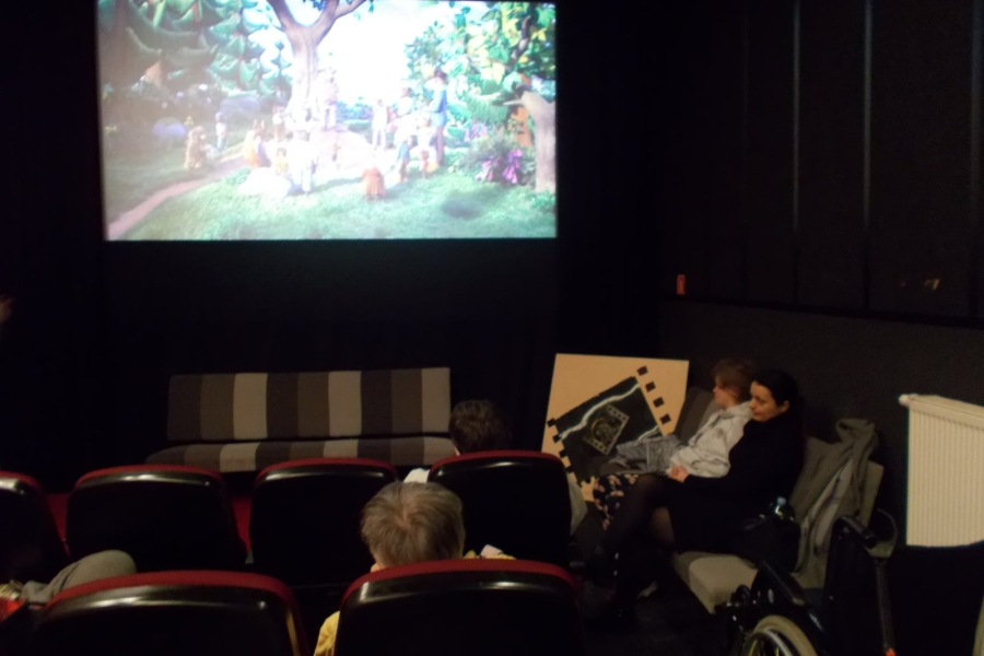 Uczestnicy siedzący na sali kinowej na tle wyświetlanego filmu