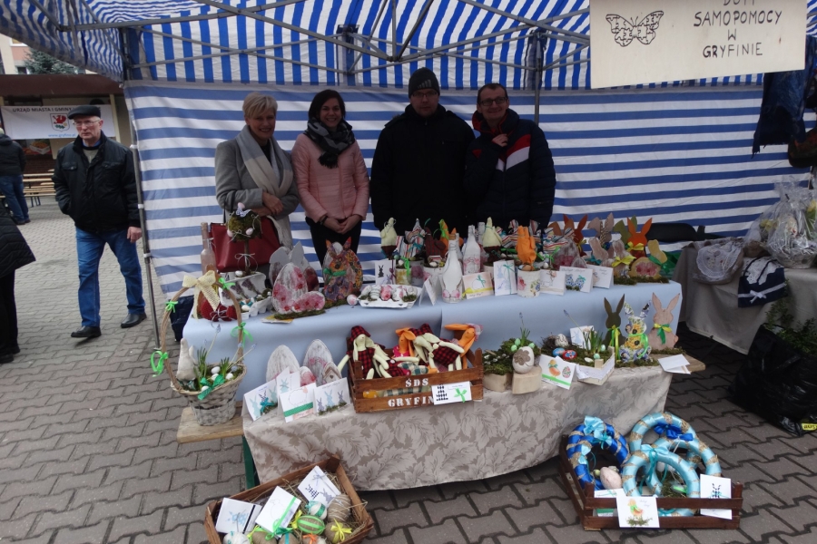 Pani Kierownik razem z terapeutką i uczestnikami ŚDS prezentują wielkanocne rękodzieło.  