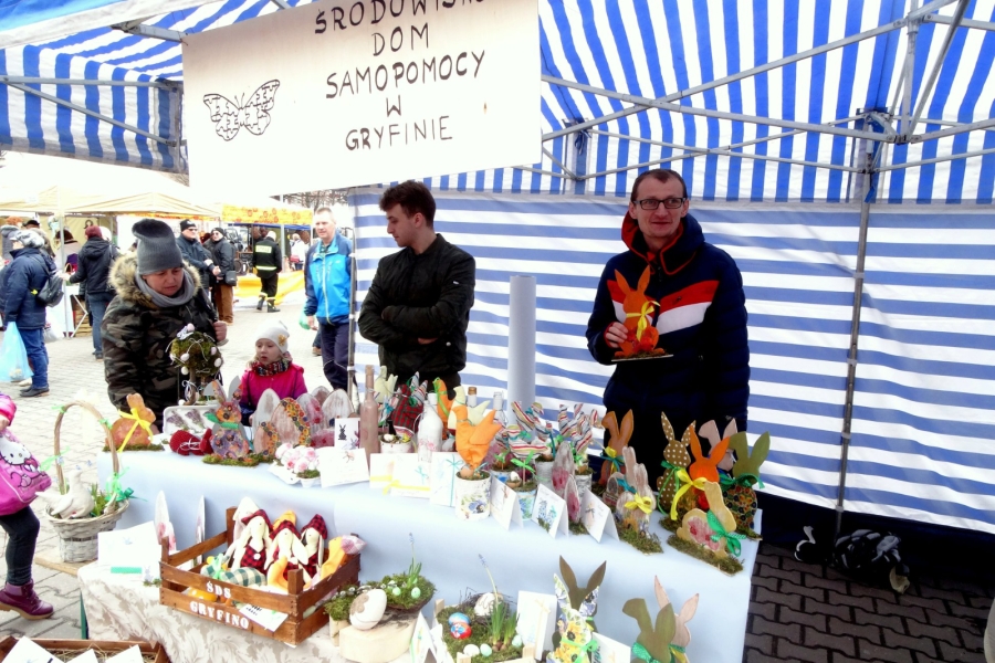  Uczestnik ŚDS na stoisku za stołem pełnym wyrobów rękodzielniczych   