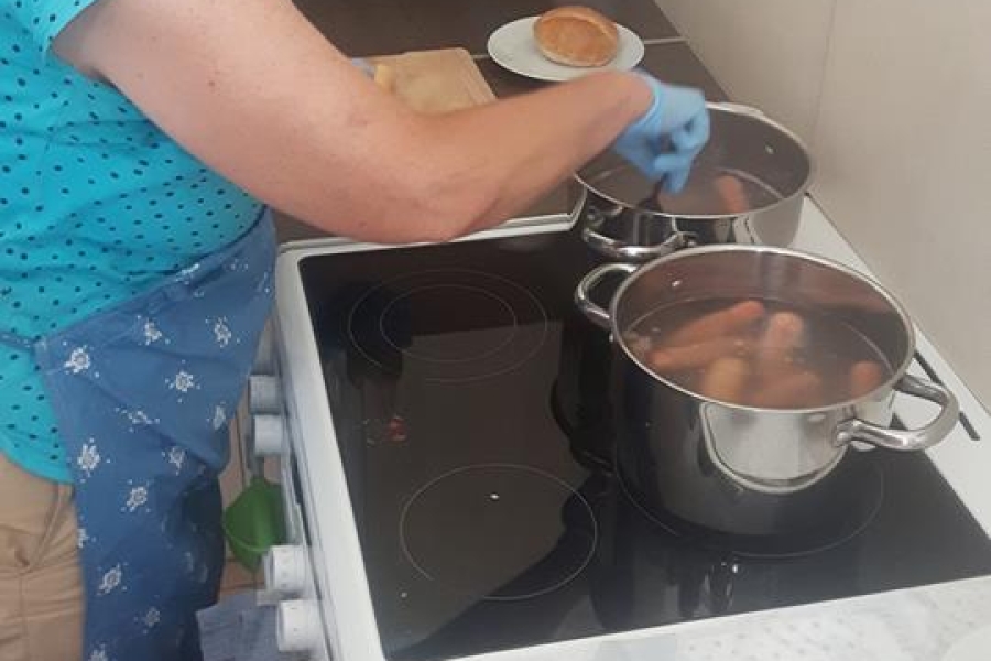 Uczestniczka w trakcie przewracania kiełbasek w gotującym się garnku.