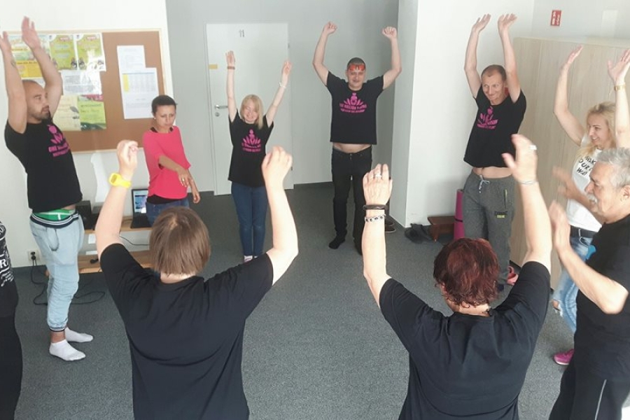 Stojący uczestnicy trzymają ręce w górze.