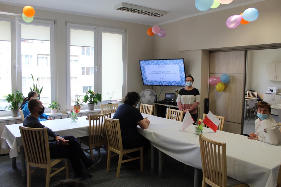 Uczestnicy siedzą przy stole podczas prelekcji na temat Dnia Osób z Niepełnosprawnością.