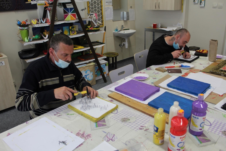 4 Uczestnicy wbijają gwoździe w pomalowane deski.